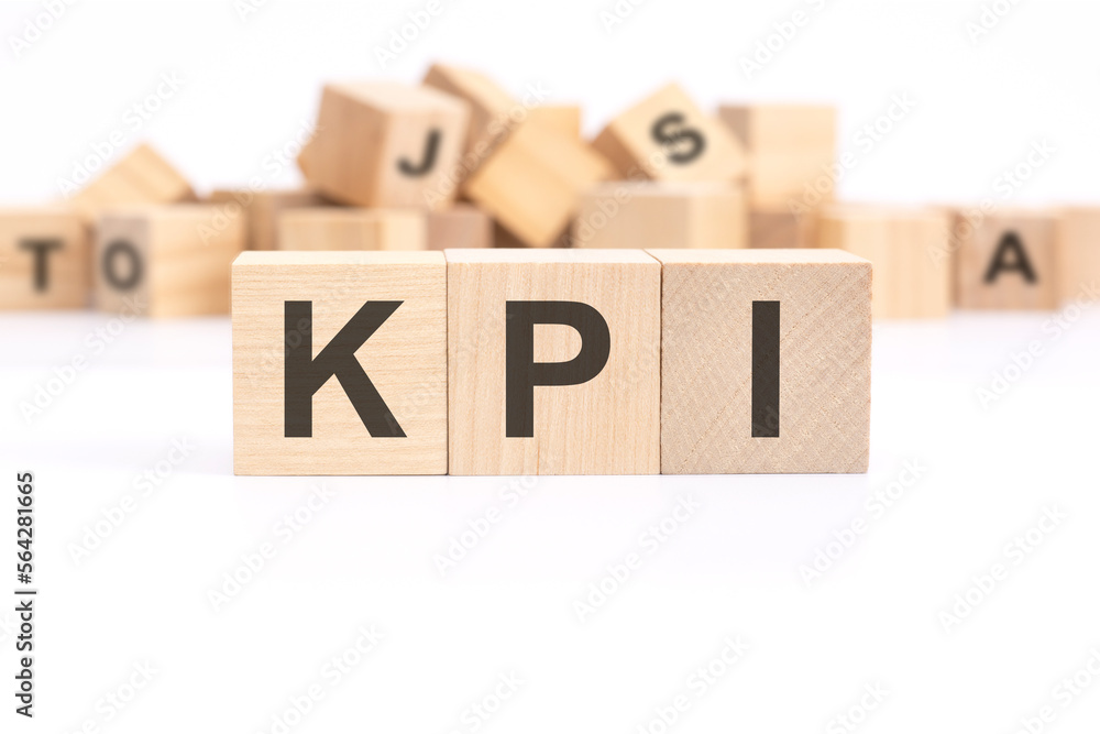 Poster text kpi - key performance indicators - is written on three wooden cubes standing on a white table. 