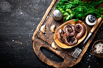 Fresh octopus on a plate on a cutting board with herbs and spices.