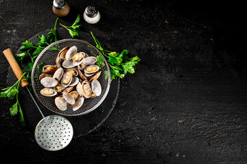 Fresh vongole in a colander on a stone board with parsley. 