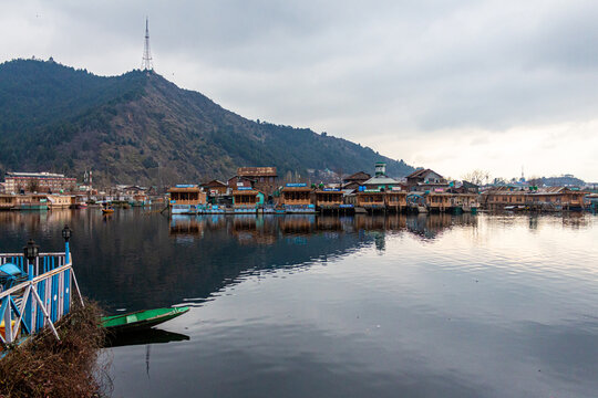 Kashmir, Srinagar India - Jan 10 2023: Popular Srinagar Houseboats in Dal Lake. Colorful Shikara ride floating in Dal Lake aka Nigeen lake. Mountain range in Srinagar. Couple Honeymoon Destination. 