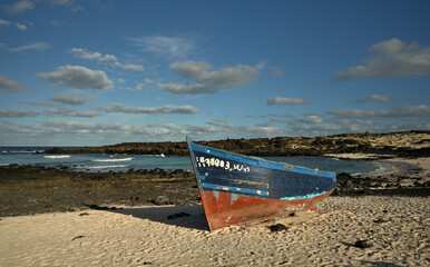 Ein Holzboot liegt verlassen an einem idyllischen Strand