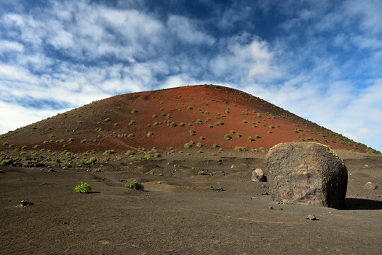 Die Caldera Colorada auf der Kanareninsel Lanzarote mit der gro&szlig;en Lavabombe bei Sonnenschein und blau wei&szlig;em Himmel