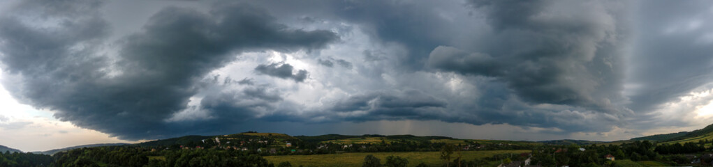Landscape of dark clouds forming on stormy sky during thunderstorm over rural area