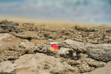 Geschliffenes, bunt schimmerndes Glas Quadrat auf einem Felsen am Strand, abstrakt und anders