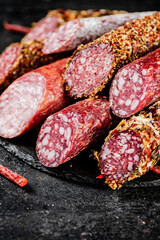 A variety of types of salami sausage with dried chili peppers on the table. 