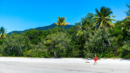 woman in red dress walking on beach in daintree rainforest national park, beach walk by tropical...