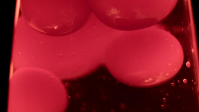 Close macro shot of red lava lamp. Moving doubles of hot red wax inside a lava lamp in front of black background.
