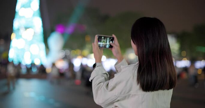 Woman use mobile phone to take photo for christmas decoration at outdoor