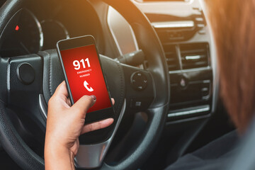 Hand holding cell phone with emergency number 911 in car
