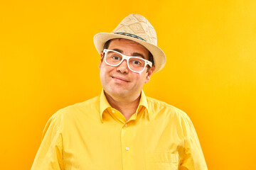 Portrait of positive fat man in hat kindly smiling isolated on yellow studio background, travel vacation concept