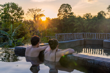 A couple in a swimming pool is watching the sunset in a jungle lodge near in Cat Tien National Park, Vietnam