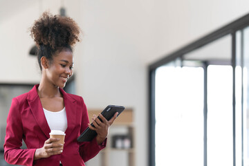Portrait of smart afro young entrepreneur woman using her digital tablet while standing looking at...