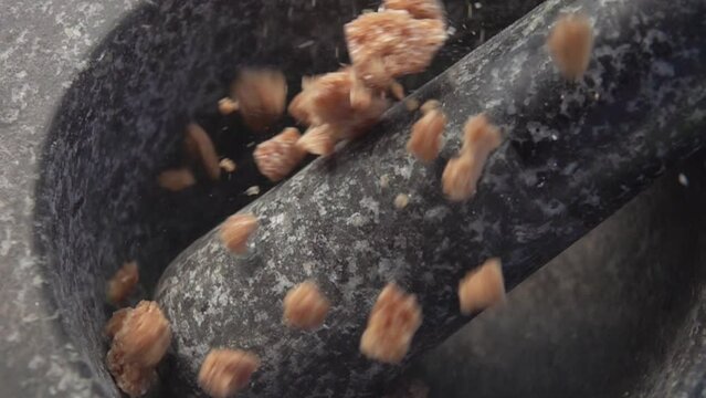 Large pieces of the sweet brown sugar are falling into the grey stone mortar