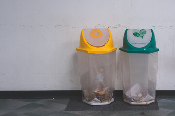 A yellow trash bin for recycle and a green trash bin for copostable with white wall background and copy space, segregate for ecosystem