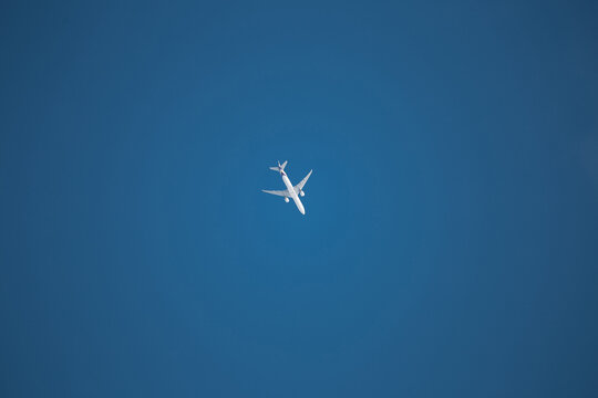 White passenger airliner in the blue clear sky - flying weather - travel by air transport