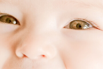 Naklejka premium Close-up portrait of a happy baby. The plump face of a newborn with a blissful smile. Sweet smile of a calm child