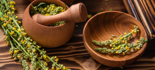 Twigs Verbascum nigrum, on a wooden table. Deep wooden mortar with black mullein, dark mullein, crushed spices. Crushing and minting of medicinal herbs 