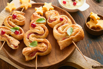 Christmas or New Year appetizer. Christmas tree shape puff pastry buns with cheese and ham. Group...