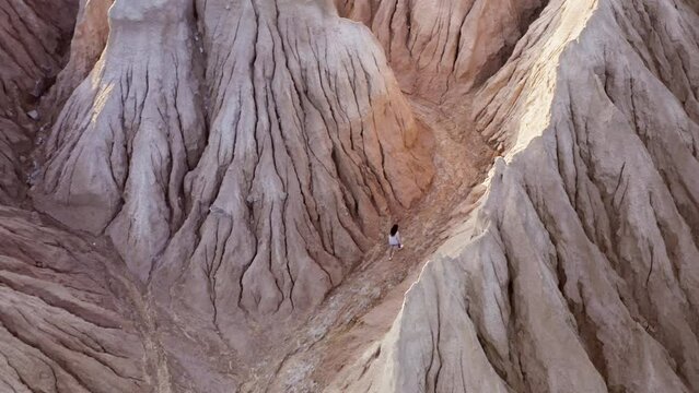 Deep sandy hills of astonishing landscape as seen from top. Aerial view of a female tourist hiking within astonishing landscape. High quality 4k footage