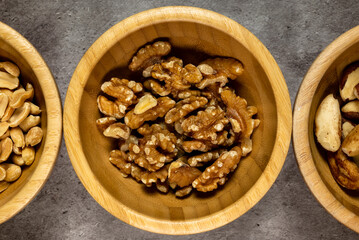 Wooden bowl with roasted nuts on a slate table. Top view, series photo with other dried fruits.