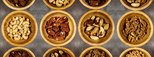 Different types of dried fruits in wooden bowls. Cashews, walnuts, pecans and brazil nuts. Top view, serial photos.