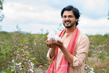 happy smiling turning by holding cotton while looking cameraat cotton field - conept of crop cultivation, Agriculture and rural india