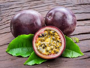 Dark purple passion fruits and it's half with seedly interior on wooden table.