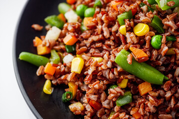 delicious red rice with vegetables on a white background