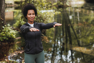 Black Woman Warming Up Before Jogging In Nature