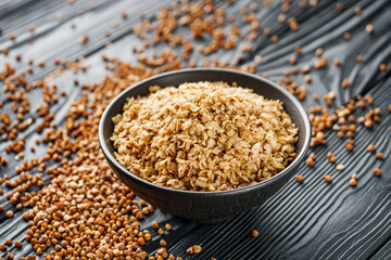 fresh raw buckwheat flakes on a black wooden background
