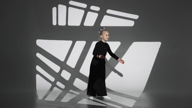 charming ittle blonde dancing like robot or doll in white background with art light pattern