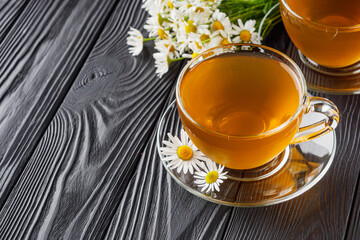 aromatic hot chamomile tea on a black rustic wooden background