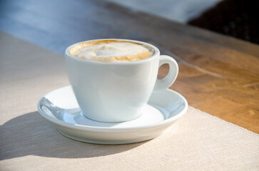 Cappuccino coffee in white cup on wood table.
