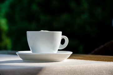 Coffee cup on wood table nature background in garden.