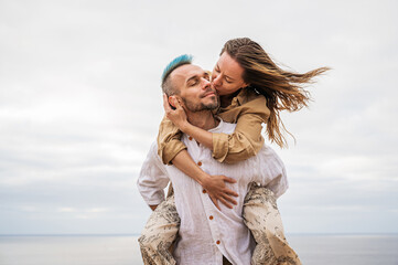 A close-up of a young couple as they kiss while the man carries the woman on his back