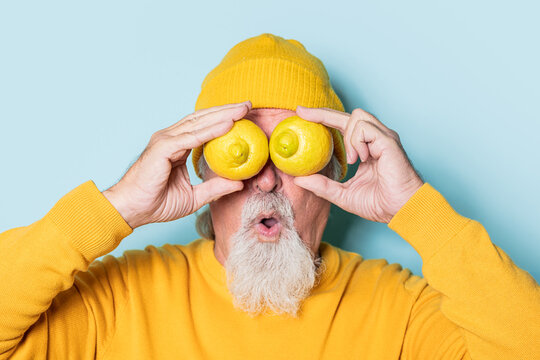 Amazed senior man covering eyes with lemons