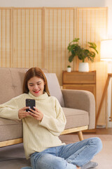 Winter holiday concept, Women sitting on floor to relax with surfing social media on smartphone