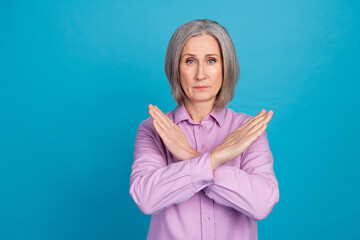 Photo of serious retied lady wear violet trendy clothes demonstrate two crossed arm near empty space isolated on blue color background