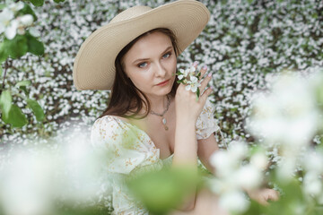 An attractive long-haired woman walks in the spring in the park of blooming apple trees.