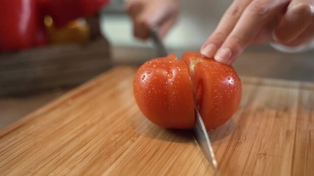 Donna taglia un pomodoro per preparare un'insalata