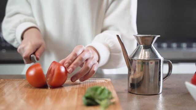 Donna taglia un pomodoro per una insalata