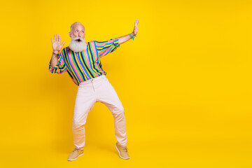 Fototapeta na wymiar Full length photo of good mood impressed guy dressed striped shirt having fun looking empty space isolated yellow color background