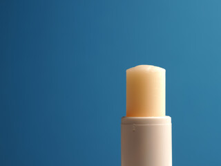 Close up of a lip balm stick on a blue background with space for your text