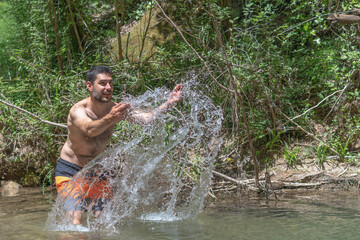 Fototapeta na wymiar man splashing water with his hands in a river