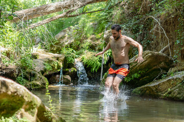 young man jumping from a rock into the water of a river