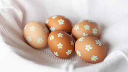 Easter eggs of natural color with painted tiny flowers a white waffle towel. Creative easy idea of decorating eggs. Neutral colors, aesthetics. Selective focus.