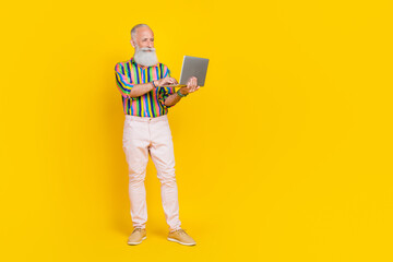 Full size photo of handsome aged person hold use netbook empty space ad isolated on yellow color...