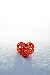 Fototapeta premium Red heart in white snow. Valentines day card, February 14 background. Red frozen heart on snowy background