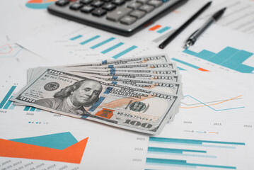 Money, business documents with infographics, calculator, pen and pencil in workplace, close-up. Accounting and financial concept. Low angle view, selective focus