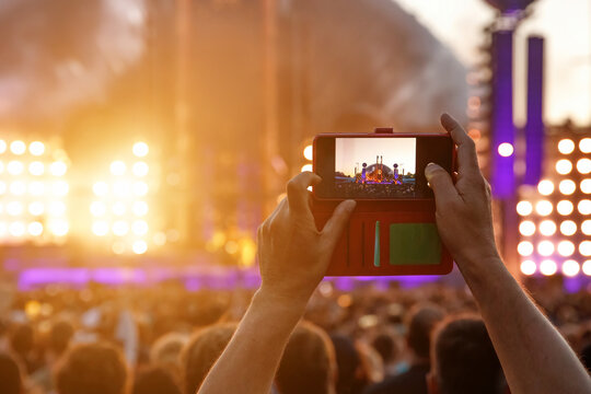 Hand with a smartphone record live music festival and taking photos of the concert.
